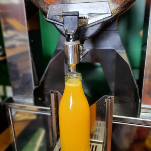 Freshly squeezed orange juice dispenser in the plastic free snacks and treats section Just Gaia zero waste grocery in Halifax, West Yorkshire